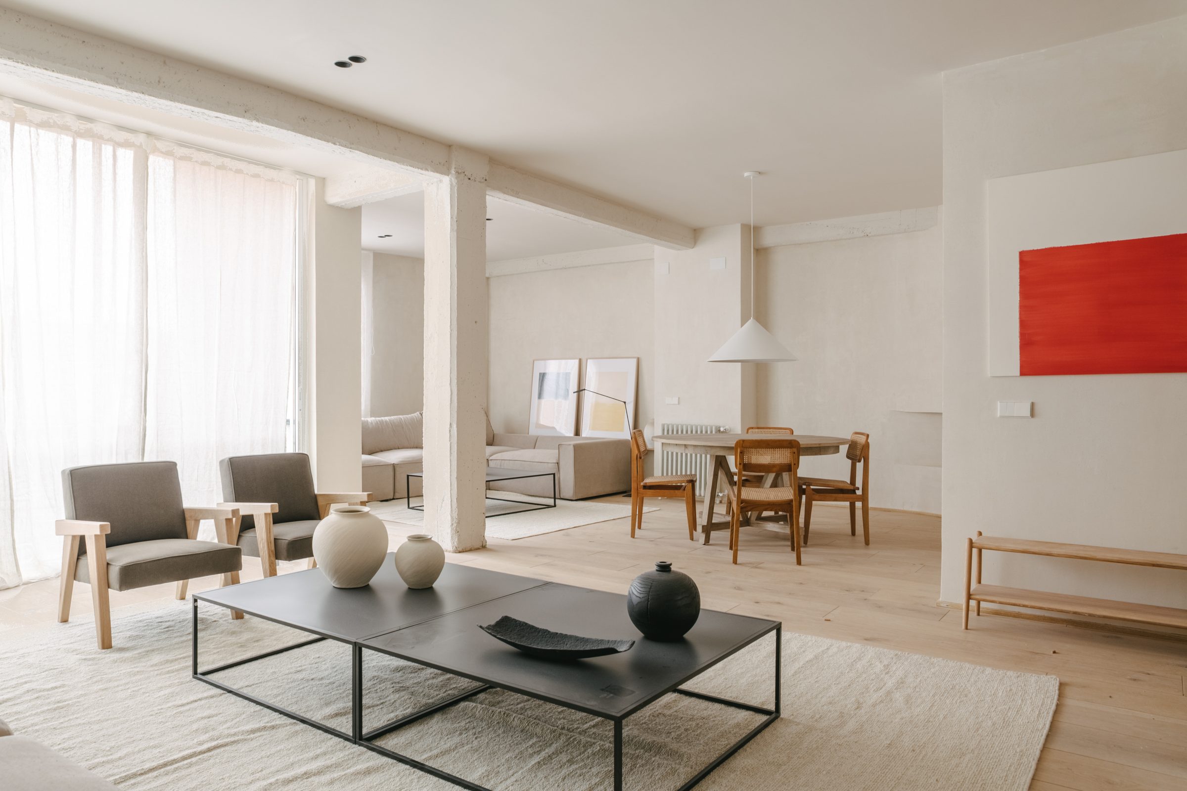 Salón amplio de vivienda rehabilitada, luminoso, con estructura vista y arte contemporáneo