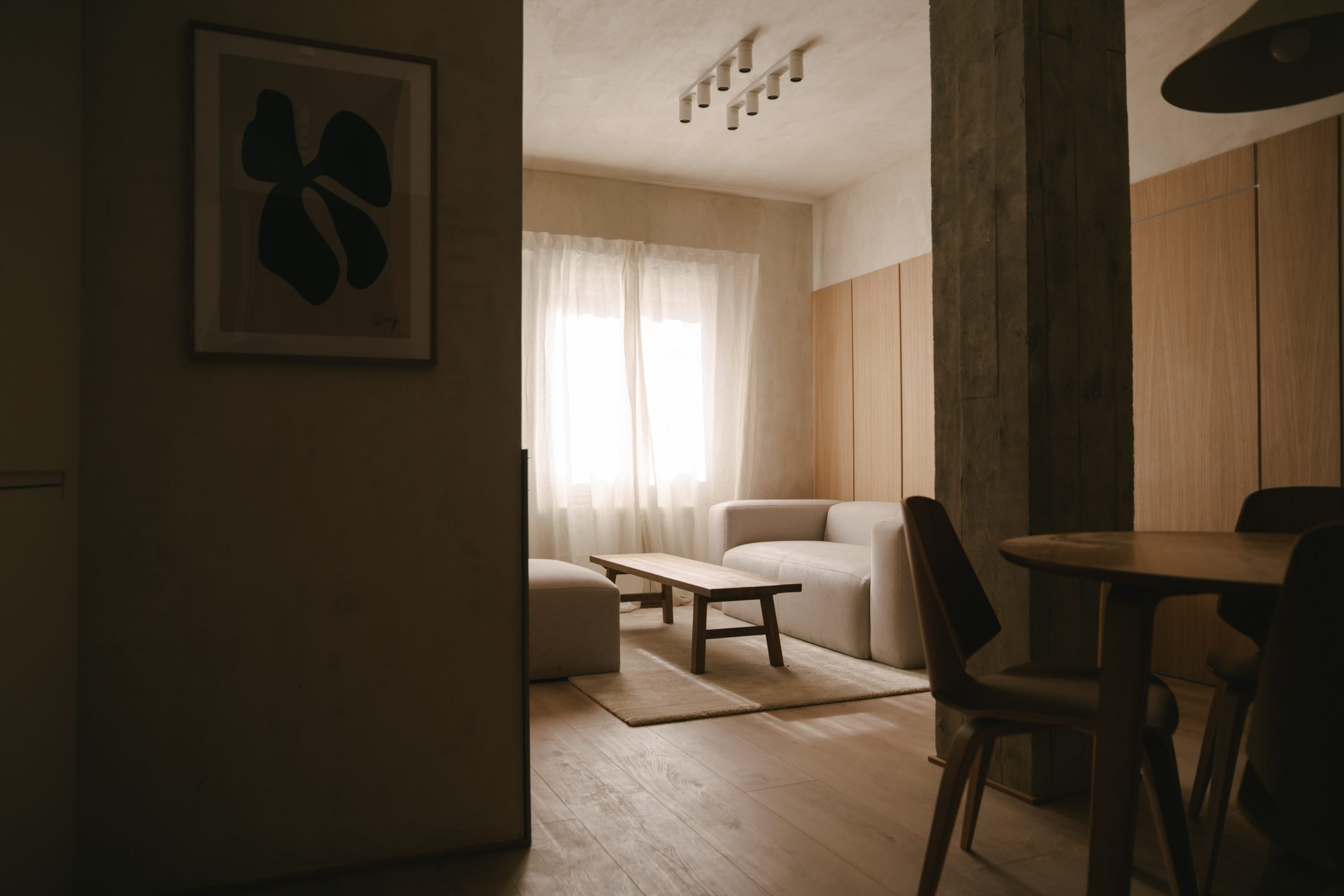 Salón cálido de vivienda rehabilitada, luz natural, madera y microcemento