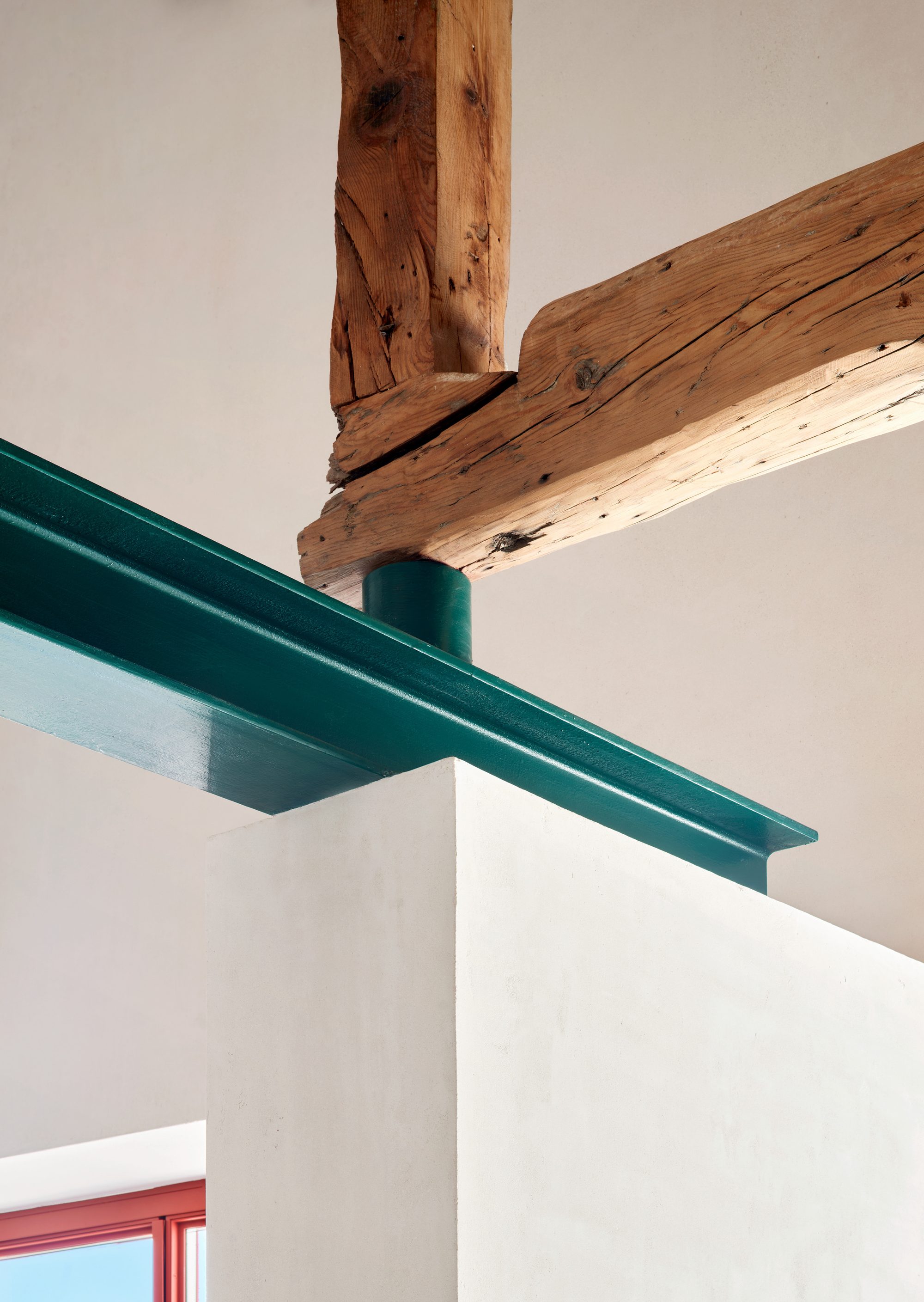 Encuentro entre viga de madera restaurada y refuerzo de acero verde